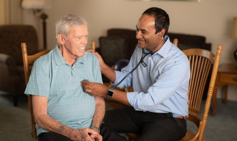 Dr. Gobi with patient Roger listening to heart with stethoscope